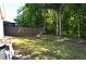 Large backyard with lush lawn and mature trees, all bordered by a wood fence for privacy at 3189 Roxmere Dr, Palm Harbor, FL 34685