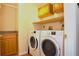Bright laundry room with a full size washer and dryer and upper and lower cabinet storage at 3189 Roxmere Dr, Palm Harbor, FL 34685