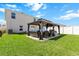 Back exterior of home and landscaped backyard featuring a covered patio with outdoor furniture and grill at 36541 Night Strawberry Ct, Dade City, FL 33525