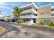 Condo building featuring stone accents, a palm tree, and lattice balconies against a partly cloudy blue sky at 4720 Locust Ne St # 206, St Petersburg, FL 33703