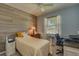 Cozy bedroom with window, ceiling fan, and a light wood accent wall at 6312 Lantern View Pl, Apollo Beach, FL 33572