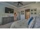 Well-lit main bedroom with tray ceiling, wood-look accent wall, large windows, carpet, and decorative furnishings at 6312 Lantern View Pl, Apollo Beach, FL 33572
