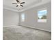 Airy bedroom with neutral carpet, tray ceiling with fan, and abundant natural light from two windows at 7336 Bagley Cove Ct, Sun City Center, FL 33573