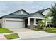 Charming single-story home featuring a two-car garage, manicured lawn, and inviting front porch with stone accents at 7336 Bagley Cove Ct, Sun City Center, FL 33573