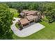 Aerial view of property featuring tile roof, expansive driveway, and lush landscaping at 7775 Still Lakes Dr, Odessa, FL 33556