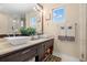 Bright bathroom featuring dual sinks, stone countertops and views to the outdoors from windows and a glass enclosed shower at 7775 Still Lakes Dr, Odessa, FL 33556