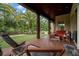Covered patio with seating, view of pond, manicured lawn and mature palm trees at 7775 Still Lakes Dr, Odessa, FL 33556