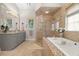 Elegant main bathroom featuring a soaking tub, glass shower, grey cabinetry, and light fixtures at 7775 Still Lakes Dr, Odessa, FL 33556