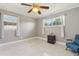 Bright bedroom featuring a ceiling fan, two windows, and a comfortable blue chair at 8408 Flagstone Dr, Tampa, FL 33615