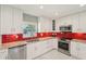 Modern kitchen featuring bright white cabinets, stainless appliances, and a vibrant red tile backsplash at 8408 Flagstone Dr, Tampa, FL 33615