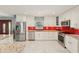 Beautiful kitchen with white cabinets, granite countertops, stainless steel appliances and unique red backsplash tiles at 8408 Flagstone Dr, Tampa, FL 33615