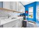 Laundry room with gray cabinets, modern appliances, and a bright blue accent wall at 10505 Inglenook Ter, Palmetto, FL 34221