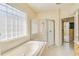 Bright bathroom featuring tile floors, glass block window, a tub, and a glass enclosed shower at 1129 Haley Ln, Dunedin, FL 34698