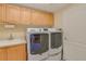 Convenient laundry room with modern washer and dryer, storage cabinets, and utility sink at 1129 Haley Ln, Dunedin, FL 34698