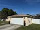 Side angle view of a attached two-car garage with adjacent green lawn and manicured shrubbery at 11708 Nicklaus Cir, Tampa, FL 33624
