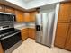 Kitchen featuring stainless steel refrigerator, wooden cabinets, and tiled floors at 11708 Nicklaus Cir, Tampa, FL 33624