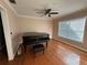 Open living room featuring hardwood floors, piano, a ceiling fan, and natural light from large window at 11708 Nicklaus Cir, Tampa, FL 33624