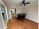 Open living room with hardwood floors, large piano, and a modern ceiling fan at 11708 Nicklaus Cir, Tampa, FL 33624