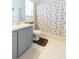 A clean bathroom with tiled floors, gray cabinets, and a seashell-themed shower curtain at 11868 Skylake Pl # 11767, Temple Terrace, FL 33617