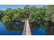 Scenic view of a wooden bridge stretching across a serene lake, lined with lush, mature trees at 11868 Skylake Pl # 11767, Temple Terrace, FL 33617