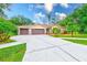 Charming single-story home features a three-car garage and a long driveway and lush green lawn at 12302 Knight Pl, Thonotosassa, FL 33592