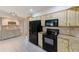 Kitchen featuring cream cabinets, granite countertops, black appliances, and tiled floors at 12302 Knight Pl, Thonotosassa, FL 33592