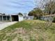 Backyard view of home, with open garage and light colored house, and grass lawn at 14616 Coral Dr, Hudson, FL 34667