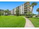 Exterior view of the condo building with a pool, lawn, and picnic tables at 19531 Gulf Blvd # 404, Indian Shores, FL 33785