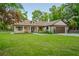 Beautiful home with covered porch, double door entry, mature trees, and green lawn at 35150 Roth Ln, Dade City, FL 33525