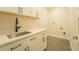 Clean laundry room featuring shaker cabinets, matte black hardware, a stainless steel sink, and tile flooring at 35150 Roth Ln, Dade City, FL 33525