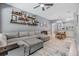 Bright living room featuring hardwood floors, grey walls, a ceiling fan, and a large comfortable sectional at 3621 Country Pointe Pl, Palm Harbor, FL 34684