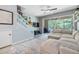 View of the living room with staircase and sectional, featuring large sliding doors to the screened-in lanai at 3621 Country Pointe Pl, Palm Harbor, FL 34684