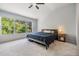 Main bedroom with large window with wood views, plush carpet, ceiling fan, and bedside tables at 3621 Country Pointe Pl, Palm Harbor, FL 34684