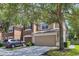 Two story tan home featuring an attached two car garage and mature shade tree at 4920 Pond Ridge Dr, Riverview, FL 33578