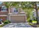 Beige two-story townhome featuring an attached two-car garage and well-maintained landscaping at 4920 Pond Ridge Dr, Riverview, FL 33578