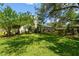 Expansive backyard featuring mature trees and landscaping with a glimpse of the screened pool at 506 Crystal Grove Blvd, Lutz, FL 33548