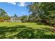 Spacious backyard with lush lawn, mature trees, and view of screened-in pool area at 506 Crystal Grove Blvd, Lutz, FL 33548