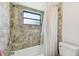 Bathroom with a tub-shower, featuring neutral-colored tile and a window for natural light at 506 Crystal Grove Blvd, Lutz, FL 33548