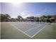 Well-maintained tennis court with a smooth surface surrounded by lush greenery and a clear blue sky at 5990 Terrace Park N Dr # 109, St Petersburg, FL 33709