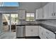 Bright kitchen featuring white cabinets, stainless steel dishwasher, and sliding doors to the outdoor patio at 6592 Mango S Ave, St Petersburg, FL 33707