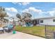 This home features a backyard with lush lawn, a tiki hut, patio furniture, and white vinyl fence at 6801 Clark St, Hudson, FL 34667