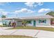 Inviting single-story home features a carport, turquoise shutters, tidy landscaping and charming curb appeal at 6801 Clark St, Hudson, FL 34667