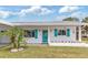 Charming single-story home featuring a well-manicured lawn, bright turquoise shutters, and a welcoming entryway at 6801 Clark St, Hudson, FL 34667