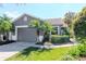 Charming single-story home with a well-manicured lawn, mature palm trees, and an attached two-car garage at 7441 Trovita Rd, Land O Lakes, FL 34637