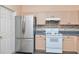 Bright kitchen with stainless steel refrigerator, white oven, tile backsplash and light wood cabinets at 7441 Trovita Rd, Land O Lakes, FL 34637