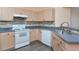 Kitchen showing updated appliances, tile backsplash, grey countertops and light wood cabinets at 7441 Trovita Rd, Land O Lakes, FL 34637