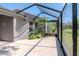 Enclosed screened patio with concrete flooring and a garden view, leading to the home's exterior at 7441 Trovita Rd, Land O Lakes, FL 34637