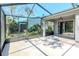 Enclosed screened patio with concrete flooring and foliage view leading to a sliding glass door at 7441 Trovita Rd, Land O Lakes, FL 34637