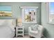 Bright bedroom with comfortable white chair and window views, featuring beach-themed artwork and ample natural light at 911 Harbour House Dr, Indian Rocks Beach, FL 33785