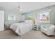 Bright bedroom with a large window, ceiling fan, beach-themed decor, and comfortable bed and chair seating at 911 Harbour House Dr, Indian Rocks Beach, FL 33785